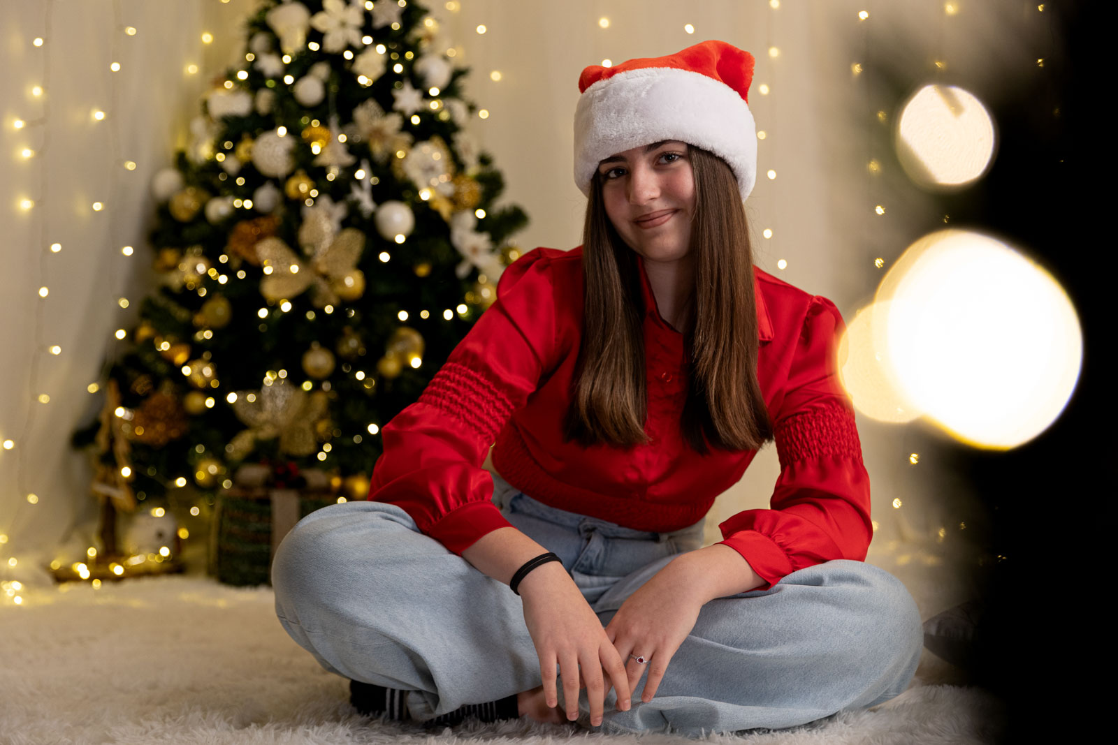 ragazza con cappello di Babbo Natale e come sfondo un albero di Natale