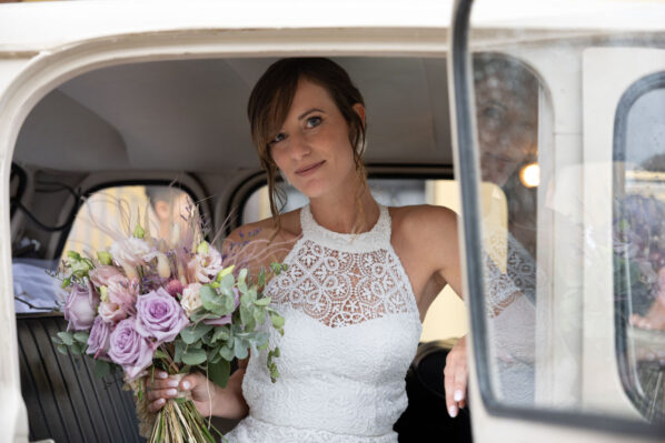 Sposa con bouquet in auto d'epoca si rilette sul finestrino