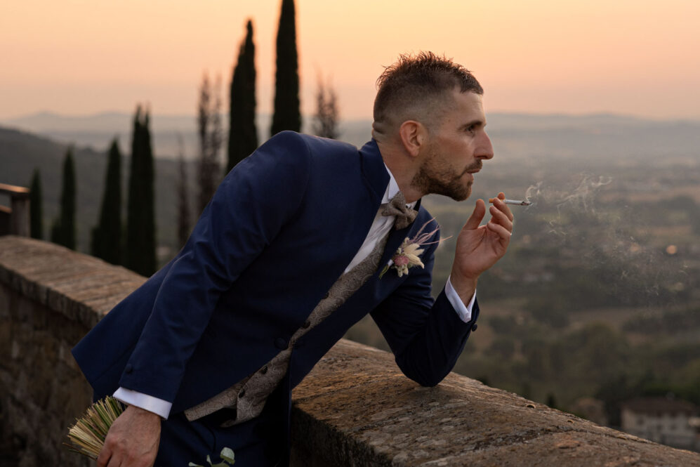 Uno sposo fuma a bettona al tramonto