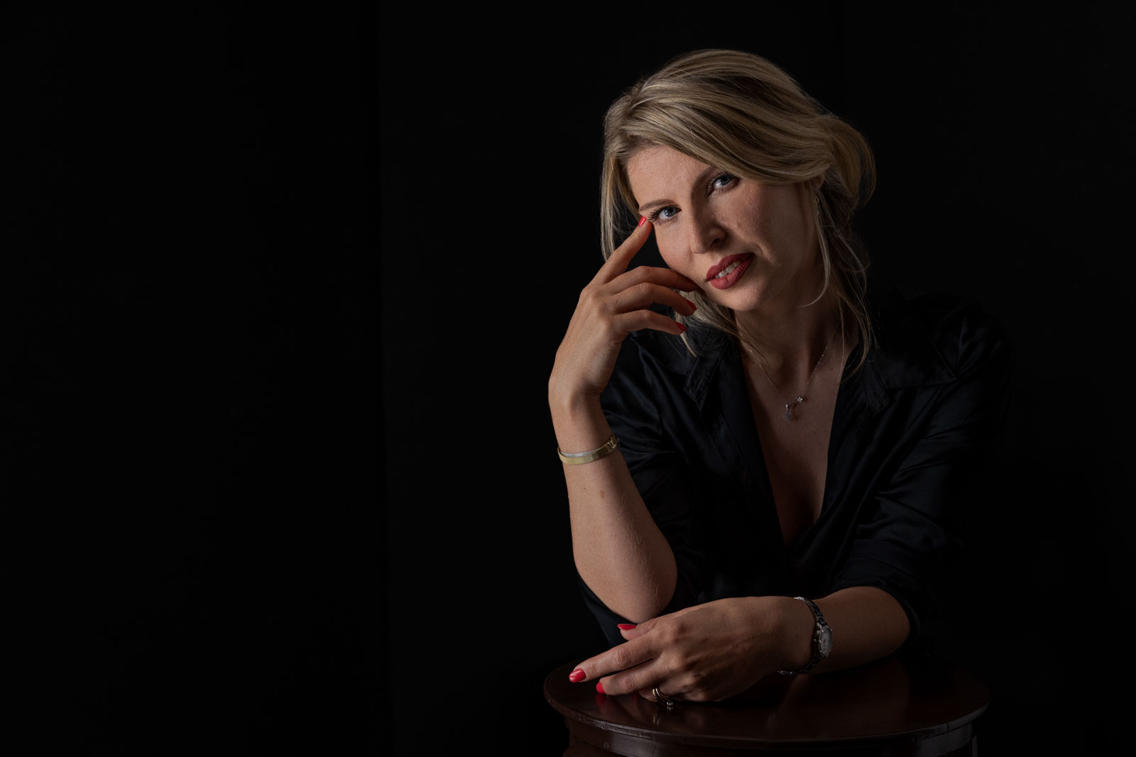 Modella bionda su sfondo nero guarda la macchina fotografica
