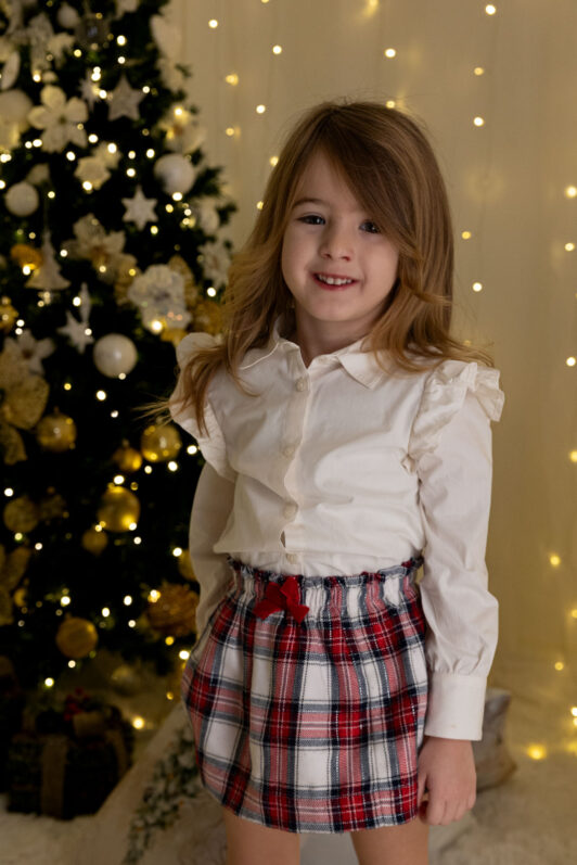 Bambina in piedi vicino all'albero di Natale