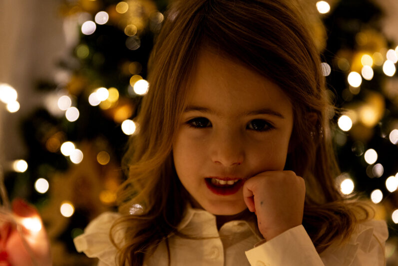 Bambina in penombra con sfondo l'albero di Natale