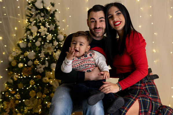 Mamma, Papà ed il loro bimbo vestiti in abiti natalizi durante un set fotografico