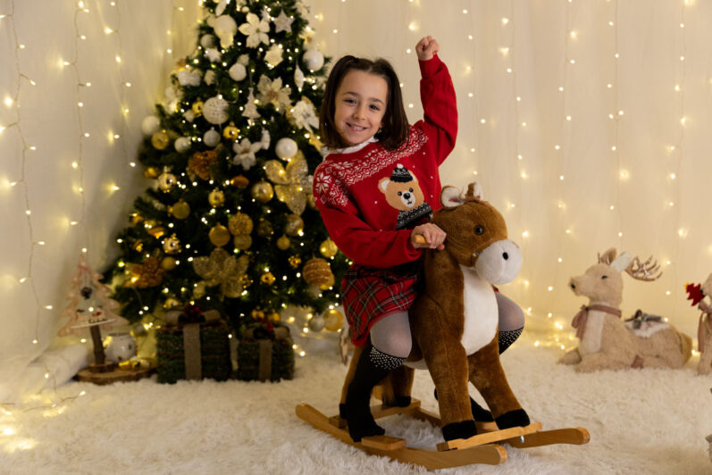 Bambina cavalca un cavallino a dondolo a Natale