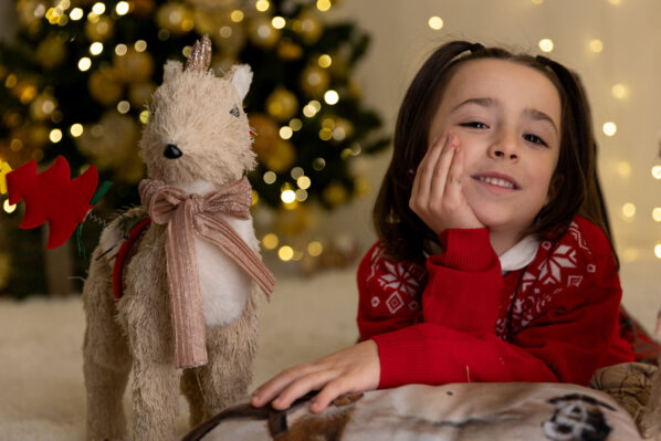 una bambina ed una peluches a forma di renna a Natale