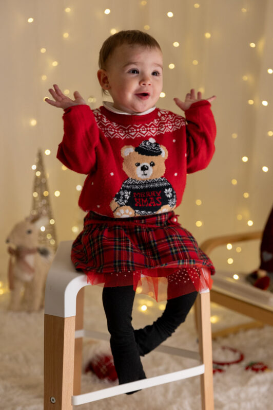 Bambina vestita natalizia ride durante un servizio fotografico