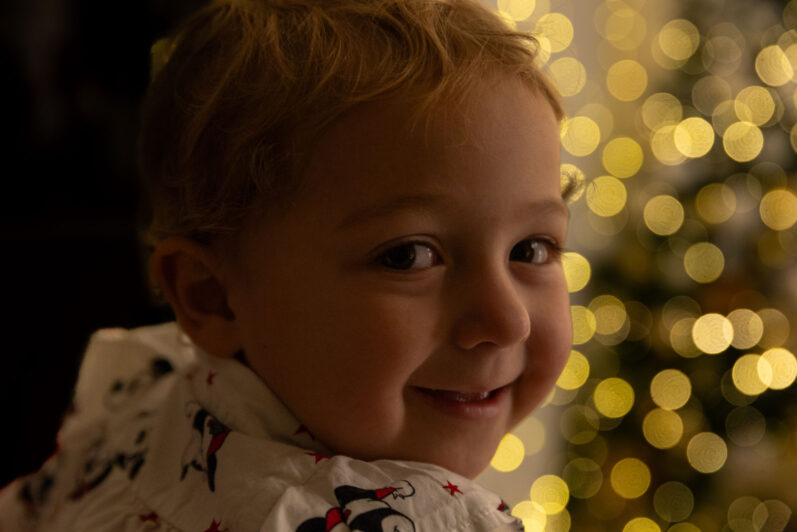 Bambino di profile con sfondo le luci di Natale durante un servizio fotografico