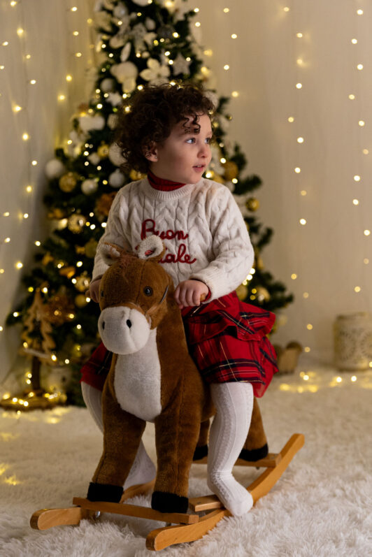 Bambina cavalca un cavallino a dondolo durante un set fotografico Natalizio ad Assisi (Perugia)