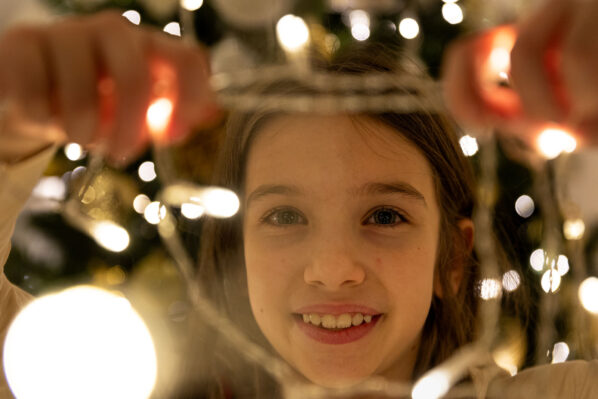 Bambina fa capolino tra le luci di Natale durante un set fotografico