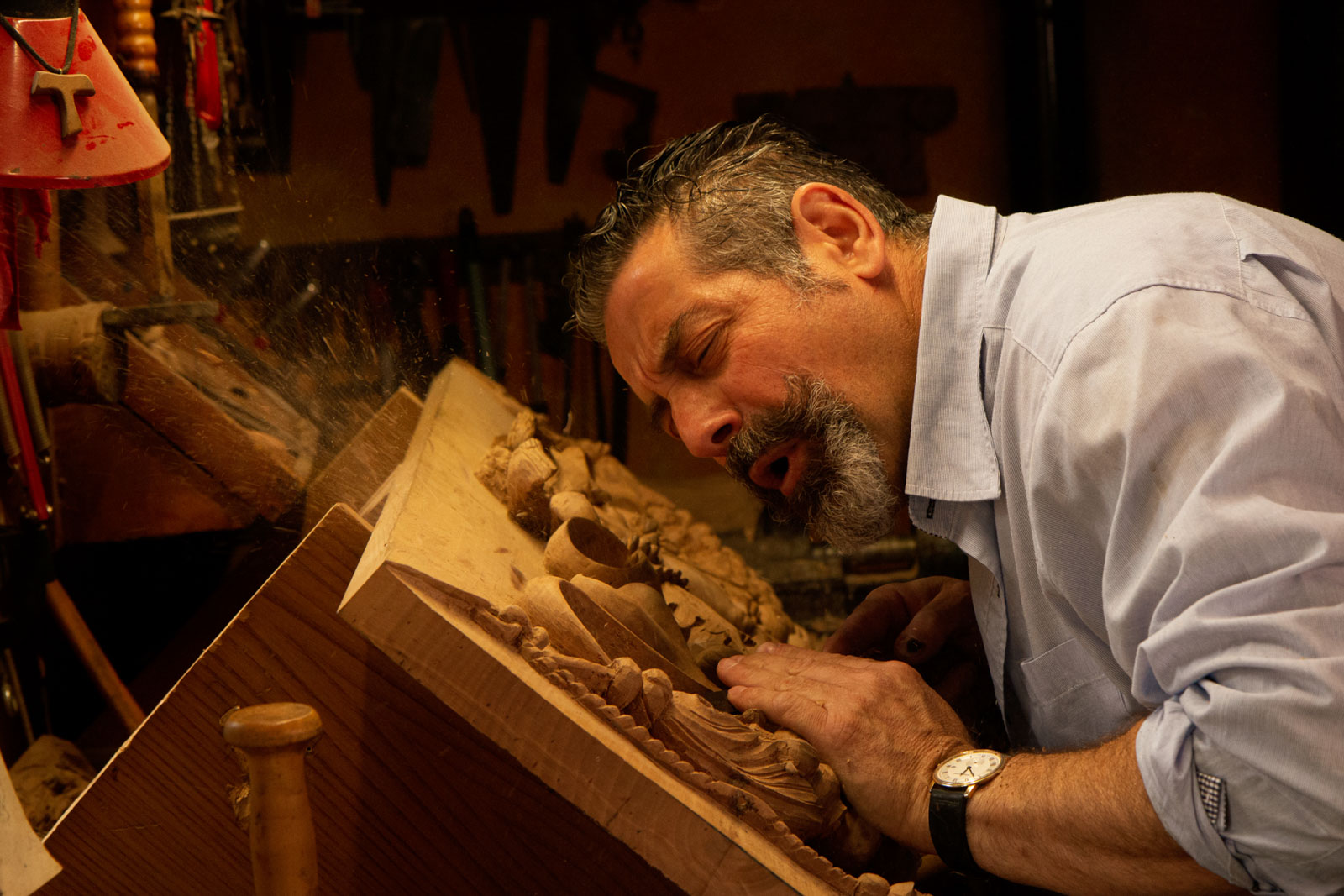 Un intagliatore soffia via la segatura dalla sua opera